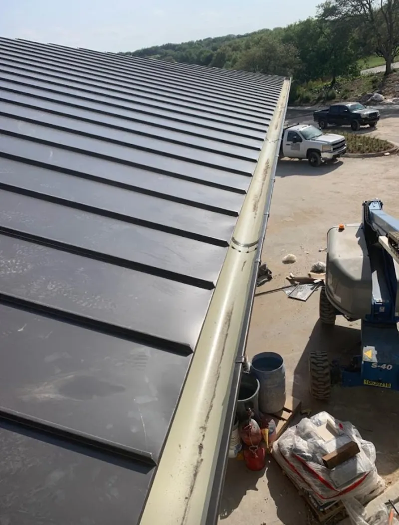 Standing seam panel and gutter detail on a metal roofing jobsite in Benton